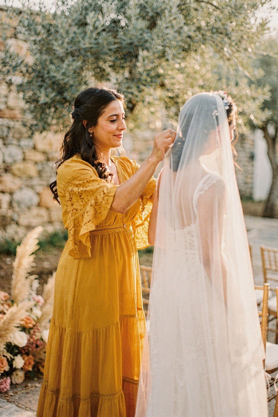 Κουμπάρα με boho φόρεμα σε ώχρα φτιάχνει το πέπλο της νύφης σε κτήμα με ελιές
